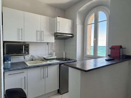 une cuisine avec des armoires blanches, un évier et une fenêtre dans l'établissement Studio cabine 3 personnes COLLIOURE AR000-C04, à Collioure
