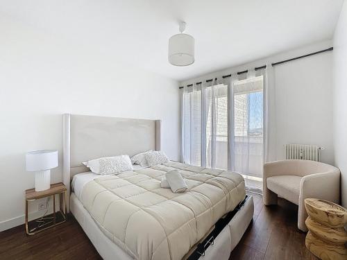 une chambre blanche avec un grand lit et une chaise dans l'établissement Appartement clair et lumineux, à Clermont-Ferrand