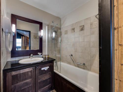 W łazience znajduje się umywalka, wanna i lustro. w obiekcie Appartement 3 pièces avec accès ski, piscine et jacuzzi à Arc 1950 - FR-1-686-21 w mieście Arc 1950