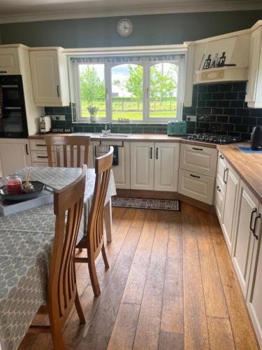 a kitchen with white cabinets and a table with chairs at Killaneen in Ballinamore