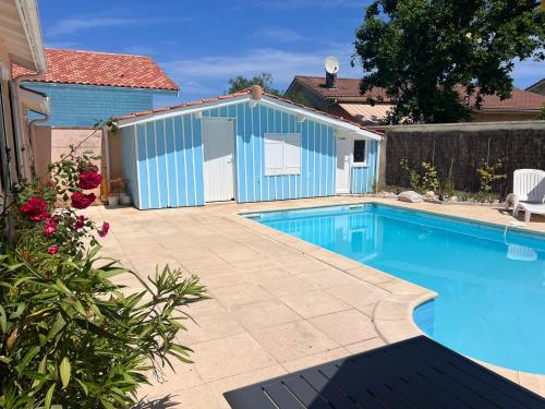 une piscine en face d'un bâtiment bleu dans l'établissement Maison avec piscine quartier pinède de conteau, à La Teste-de-Buch