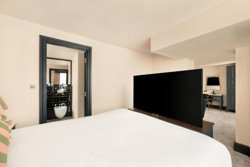 a bedroom with a large bed with a flat screen tv at Hotel Indigo London - Kensington by IHG in London