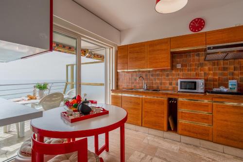 une cuisine avec des placards en bois et une table rouge dans l'établissement LE CHANTILLY AP4464 by RIVIERA HOLIDAY HOMES, à Cagnes-sur-Mer