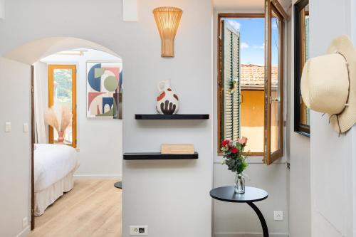 Cette chambre comprend un lit et un vase avec des fleurs sur une table. dans l'établissement VIEUX CHATEAU II - Agréable 2 pièces - Vue Mer - Menton Vieille Ville, à Menton