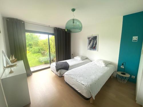 une chambre avec deux lits et une grande fenêtre dans l'établissement Villa de la Pointe, à Saint-Pabu