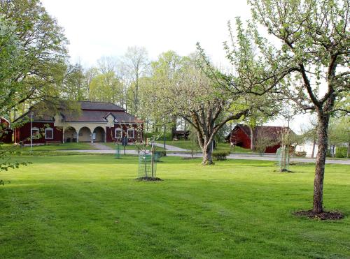 a house in a green field with trees in front of it at Stora Djulö Vandrarhem in Katrineholm