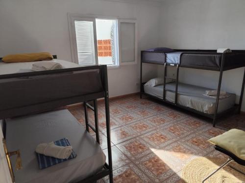 a room with three bunk beds and a window at Hostel Banana Surf House in Los Cristianos