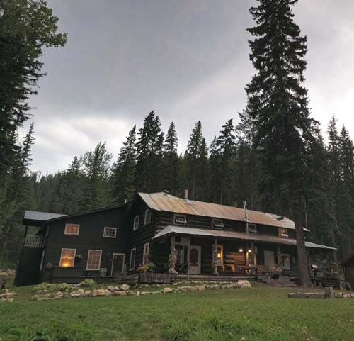 a large black house in the middle of a field at Rustic Beaverfoot Lodge Room N10 in Parson