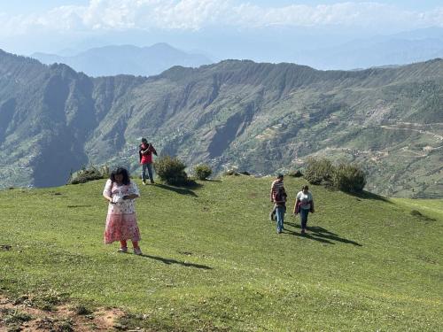 a group of people walking on a grassy hill at Apple Land by Naavagat in Jibhi