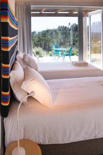a bedroom with a bed and a large window at Vale das Estrelas in São Teotónio