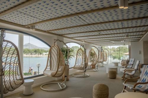 a row of chairs and tables in a room with windows at Hotel Moré in Alcudia