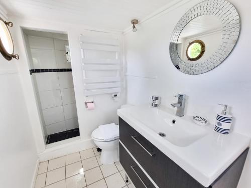une salle de bain blanche avec un lavabo et un miroir dans l'établissement EXIGEHOME - Péniche 120 m2 en bord de Seine calme et verdoyant, à Le Port-Marly