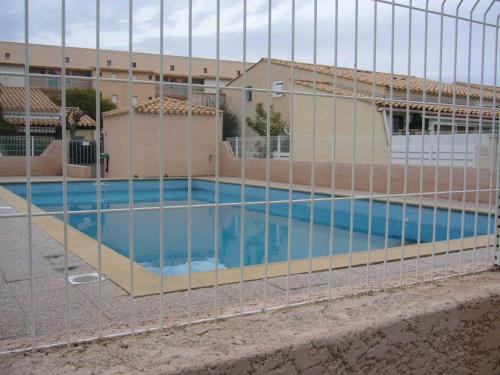 une piscine entourée d'une clôture dans l'établissement Appartement avec chambre et mezzanine à proximité de la mer, au Cap d'Agde
