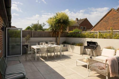 a patio with a table and chairs and a fence at Chic 4-Bed Coastal Retreat in Heart of Bosham in Bosham
