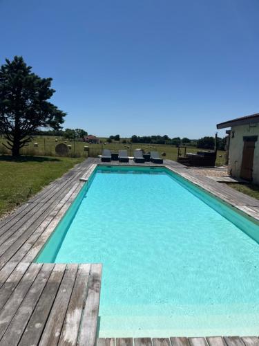 une grande piscine avec une terrasse en bois dans l'établissement Villa Jourdain, à La Genétouze