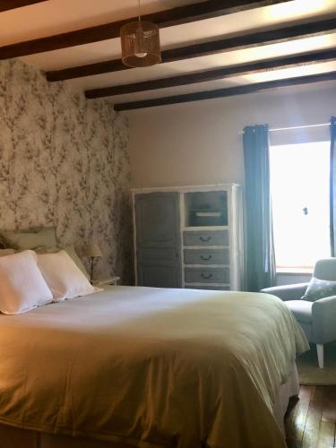 une chambre avec un lit, une chaise et une fenêtre dans l'établissement Le Cerisier Saint-Barbant, à Saint-Barbant