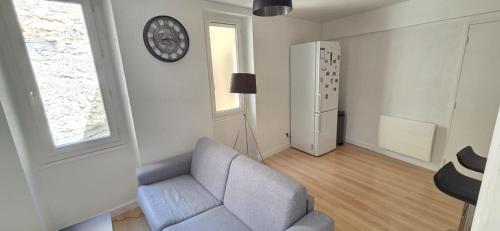 a living room with a couch and a clock on the wall at T2 cœur de ville avec terrasse in Agen