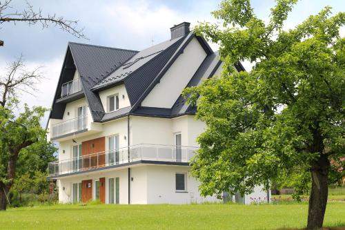 a large white house with a black roof at Apartamenty w sadzie in Przenosza