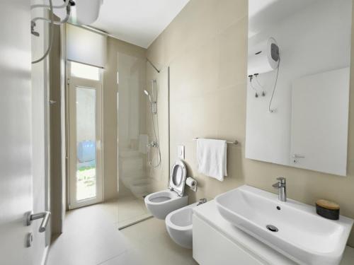 een witte badkamer met een wastafel en een toilet bij Mèla Twin Villa Green Coast in Himare