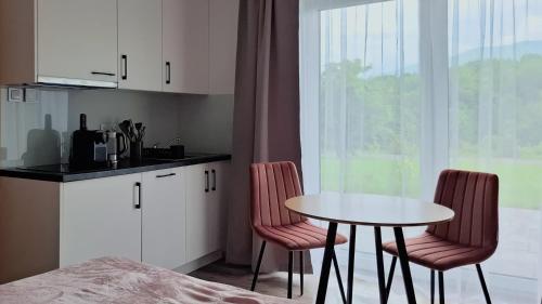 a kitchen with a table and two chairs and a table at Apartamenty w sadzie in Przenosza