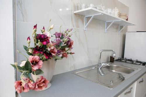 a vase of flowers on a counter next to a sink at Appartamento Centrale Scalea in Scalea