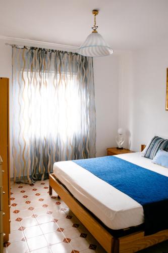 a bedroom with a bed with a blue blanket and a window at Appartamento Centrale Scalea in Scalea