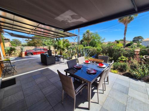 un patio avec une table et des chaises sur un patio dans l'établissement Villa 2 chambres de plain pied, climatisation, internet plages et commerces à proximité, à La Seyne-sur-Mer