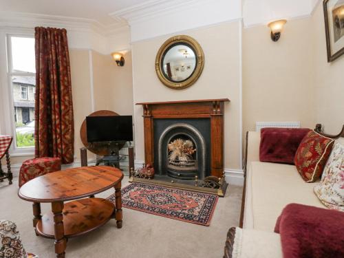 Una sala de estar con chimenea y un sofá. en Robin's Retreat, en Kendal