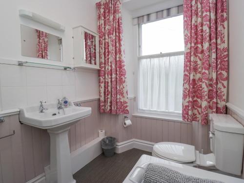 Un baño con lavabo, inodoro y ventana. en Robin's Retreat, en Kendal