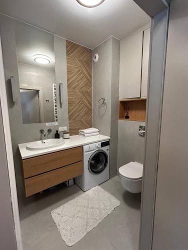 a bathroom with a sink and a washing machine at Tutu Kraków Comfort in Krakow