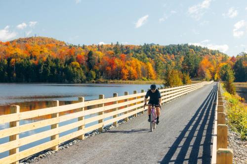 a person riding a bike on a bridge over a river at voco Saranac Lake NY - Waterfront by IHG in Saranac Lake