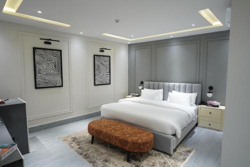 a bedroom with a large white bed and a stool at The Khushi Hotel And Resorts in Murree