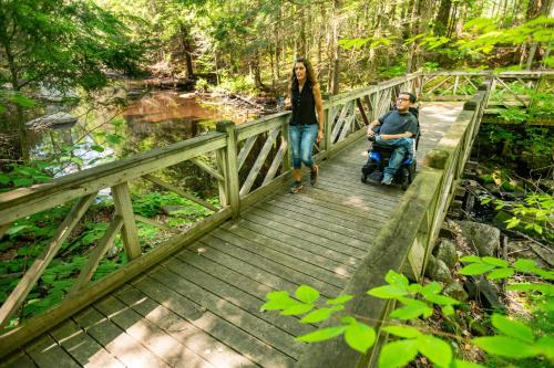 a woman and a man on a bridge with a wheelchair at voco Saranac Lake NY - Waterfront by IHG in Saranac Lake