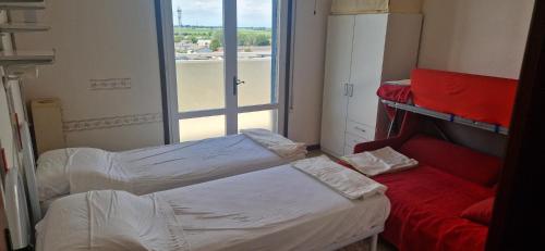 two beds in a small room with a window at Attico Alvorada in Porto Santa Margherita di Caorle