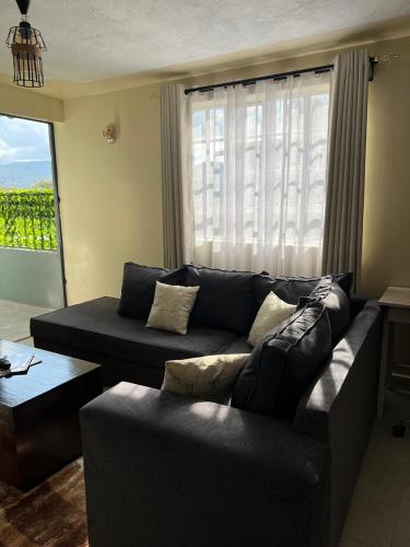 a living room with a black couch and a window at Noble Park Apartments in Kiserian