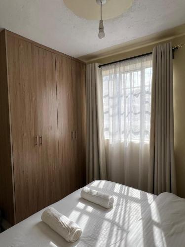 a bedroom with a bed with two towels on it at Noble Park Apartments in Kiserian