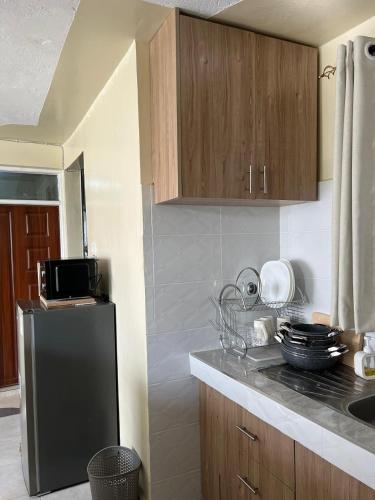 a kitchen with a black refrigerator and wooden cabinets at Noble Park Apartments in Kiserian