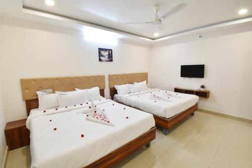 a hotel room with two beds and a television at Cannan Residency in Pūrnānkuppam