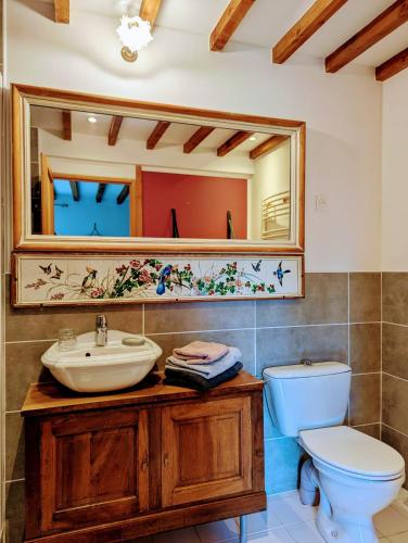 une salle de bain avec un lavabo, des toilettes et un miroir dans l'établissement Maison d'hôtes Trip'n Touille, à La Fourche
