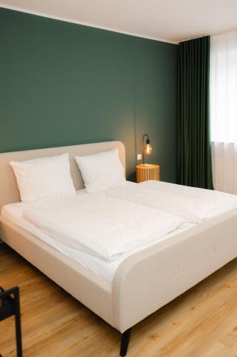 a large white bed in a room with a green wall at Fährhaus Kollmar in Kollmar