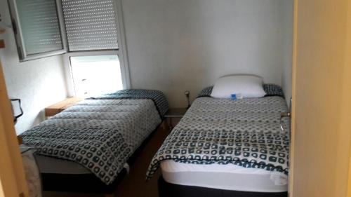 deux lits dans une petite pièce avec une fenêtre dans l'établissement Grand T3 entrée Arcachon rénové, à Arcachon
