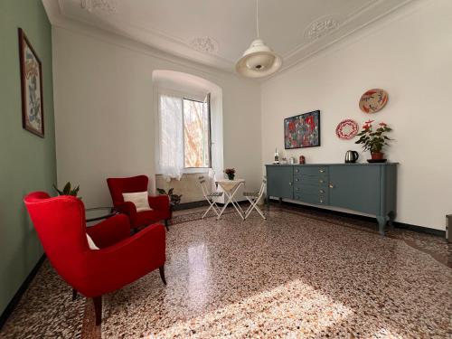 a living room with red chairs and a dresser at Affittacamere Sorighittu in Genova