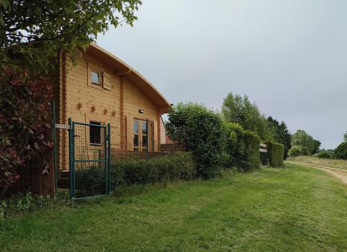 a building with a gate on the side of a field at Le chalet des Sarteaux in Ville-sur-Lumes