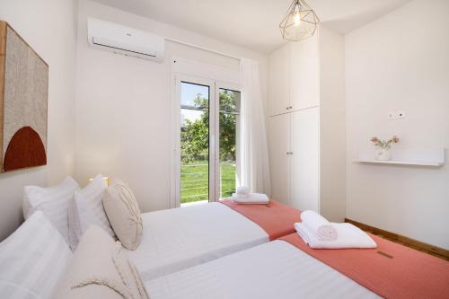 a white bedroom with two beds and a window at Villa Prinos Private Pool in Plaka