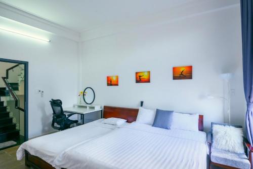 a bedroom with a large white bed and a desk at Lama Homestay in Hue