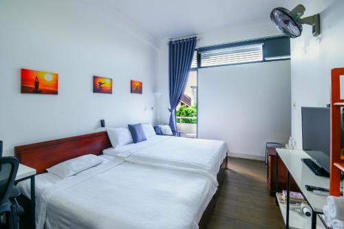 a bedroom with two beds and a desk and a window at Lama Homestay in Hue