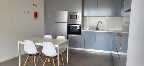 a kitchen with a table and some white chairs at Casa Azul in Costa Nova