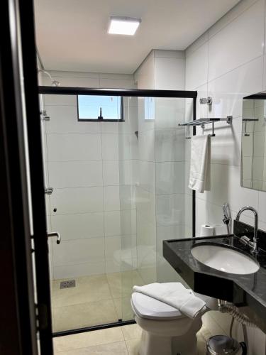 a bathroom with a shower and a toilet and a sink at Hotel Accordes in Campo Grande