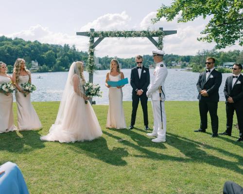 a bride and groom standing under a ceremony altar at voco Saranac Lake NY - Waterfront by IHG in Saranac Lake