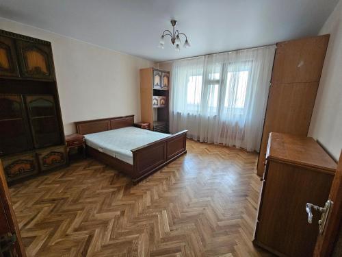 a bedroom with a bed and wooden floors and a window at Dendro House in Chişinău